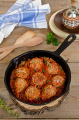 Fried meatballs with tomato sauce and spices in frying pan
