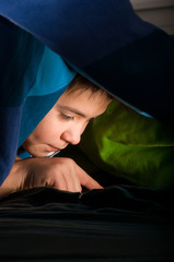 boy reading a book under the covers