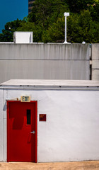 Red door and exit sign on small building in Towson, Maryland.