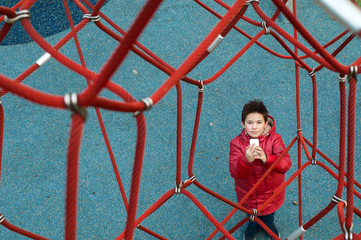 Boy with phone on the playground in the park