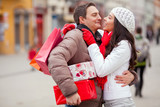 Happy young couple exchanging holiday gifts outdoors.