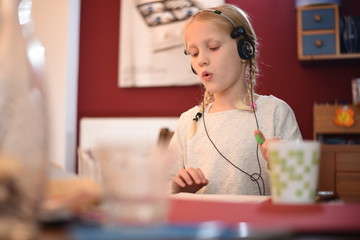 Kleines Mädchen mit Kopfhörern macht Hausaufgaben