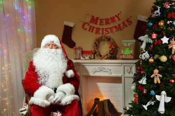 Santa Claus sitting in comfortable chair near fireplace at home