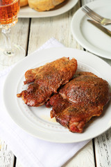 Roasted meat on plate, on wooden table background