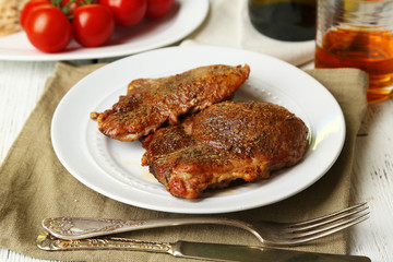 Roasted meat and vegetables on plate, on wooden table