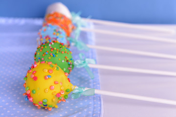 Sweet cake pops on table on blue background