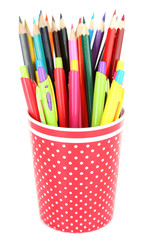 Colorful pens and pencils in red polka-dot plastic cup isolated