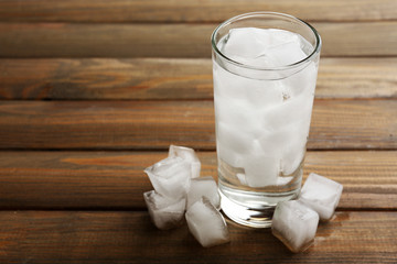 Glass with ice cubes on wooden table