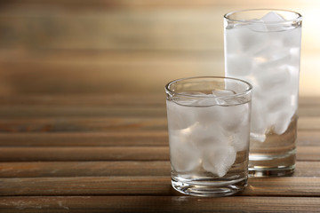 Glasses with ice cubes on wooden table