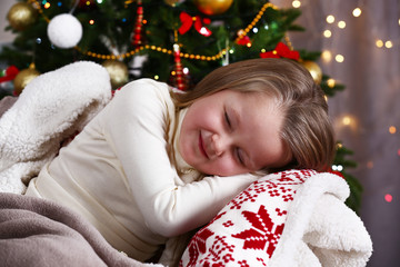 Little girl sleeping on Christmas tree background