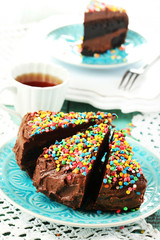Chocolate cake with colorful sweet powder on table close-up