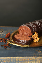 Delicious roll cake on wooden table, on dark background