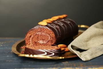 Delicious roll cake on wooden table, on dark background