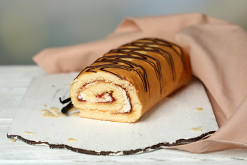 Delicious roll cake on wooden table, on light background