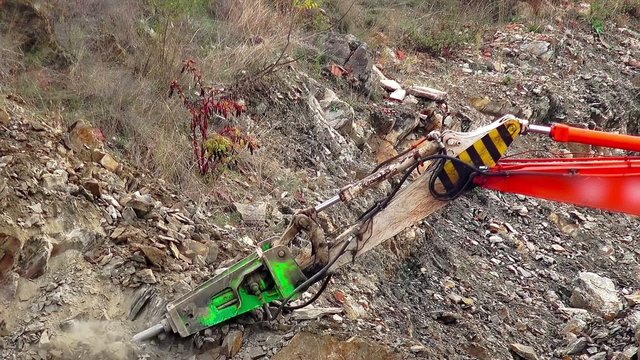 Large jackhammer construction machinery smashing rocks. Excavator breaking and drilling stone in hill open mine. Sony 4K shot