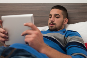 Male Teenager With Touch Pad On Bed