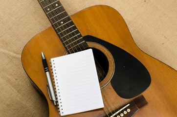 Naklejka premium blank paper with pen on old acoustic guitar