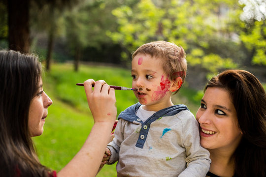 Happy mother painting her child´s face in the park