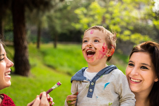 Happy mother painting her child´s face in the park