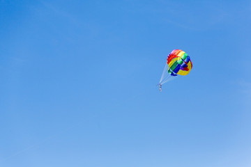 people against the sky, flying with a parachute