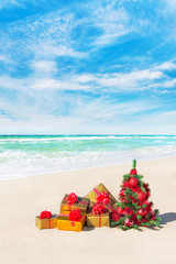 Christmas tree and gift boxes on sandy beach