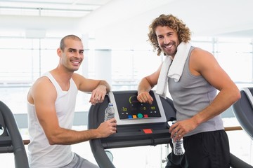 Smiling male trainer and fit man at gym