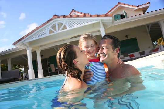 Family Playing In Swimming Pool Of Private Villa