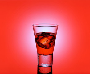 Short drink glass with red liquid and ice cubes