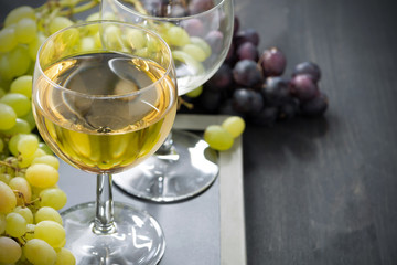 glass of white wine and grapes on a blackboard, horizontal