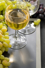 glass of white wine and grapes on a blackboard, vertical