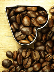 Heart and Coffee beans close-up on wooden, oak table.