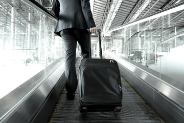 Businessman with bag going up on the escalator at the airport