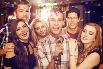 Obraz na płótnie Canvas Composite image of happy friends singing karaoke together