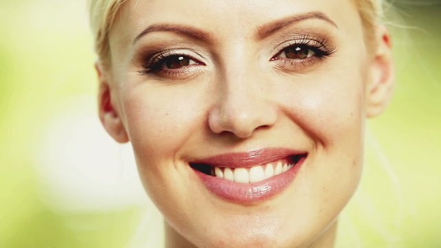 Attractive blonde young woman smiles into the camera. Close up