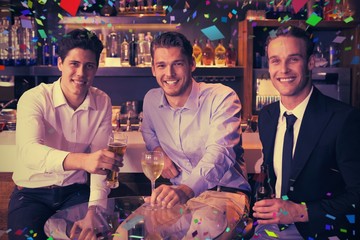 Composite image of handsome friends having a drink together