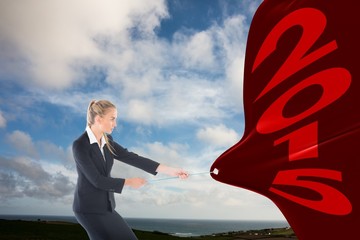 Composite image of focused blonde businesswoman pulling a rope