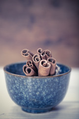 Bunch of cinnamon sticks in the bowl on wooden background 