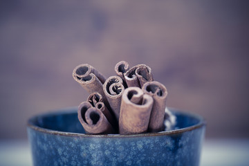 Bunch of cinnamon sticks in the bowl on wooden background 