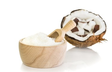Desiccated coconut in wooden bowl with scoop on white background