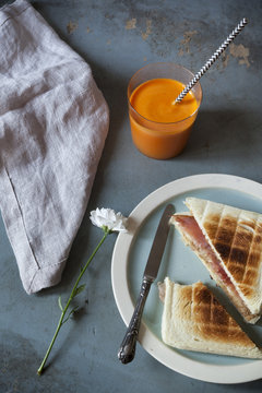 toasted sandwich with orange carrot smoothie on table