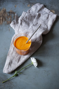 orange carrot smoothie on glass on table with white flower