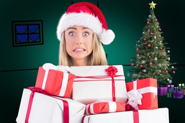 Composite image of festive blonde holding pile of gifts