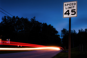 Long exposure of cars passing by a speed limit sign.