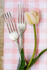 The two dessert forks are near tulip on a tablecloth