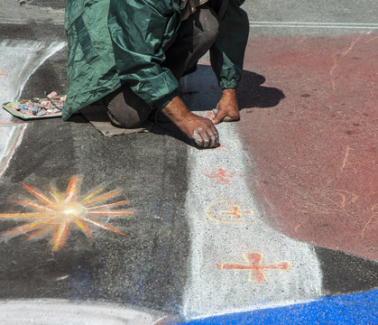 artist paints with colorful chalks on the street image of saints