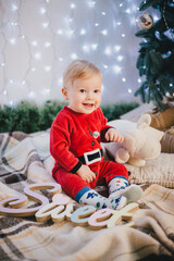 Naklejka premium Baby-boy in Santa Claus suit sitting under the Christmas tree