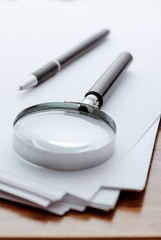 Magnifying glass, ballpoint pen on white paper for notes