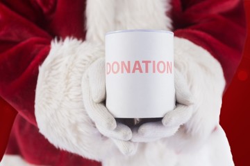 Obraz na płótnie Canvas Composite image of santa holds a can for donations