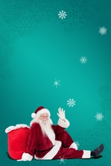 Composite image of santa sits leaned on his bag and waves