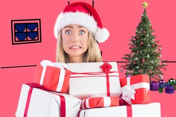 Composite image of festive blonde holding pile of gifts